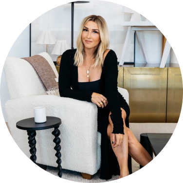 Woman in black dress sitting on a white armchair in a modern room.