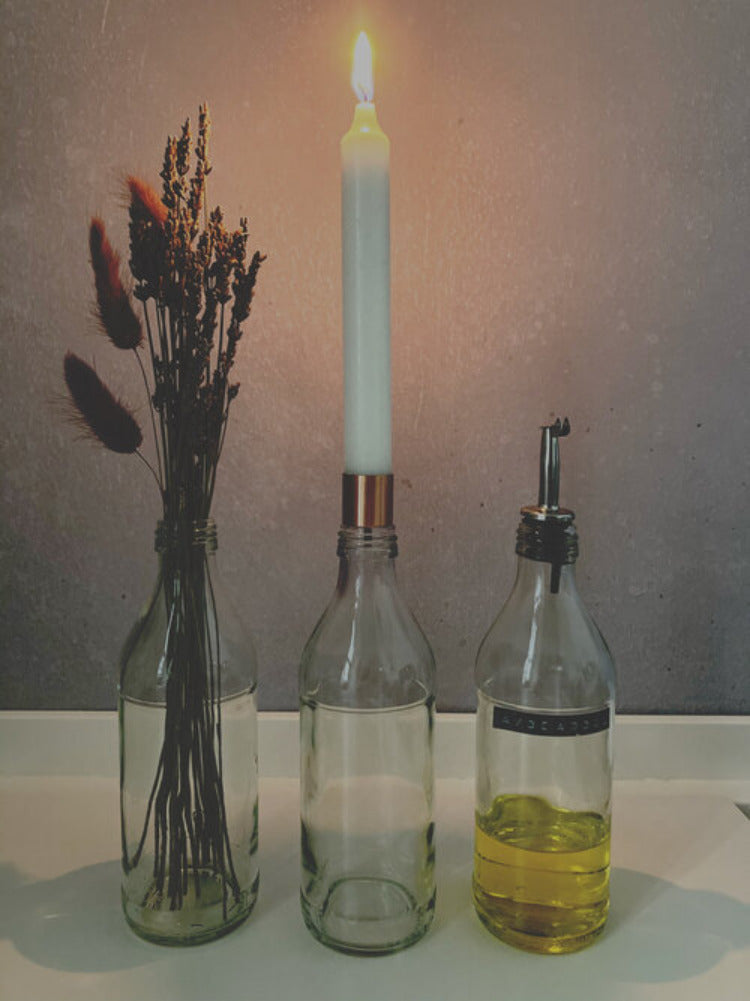 Three kombuchery bottles as a vase candle holder and oil bottle