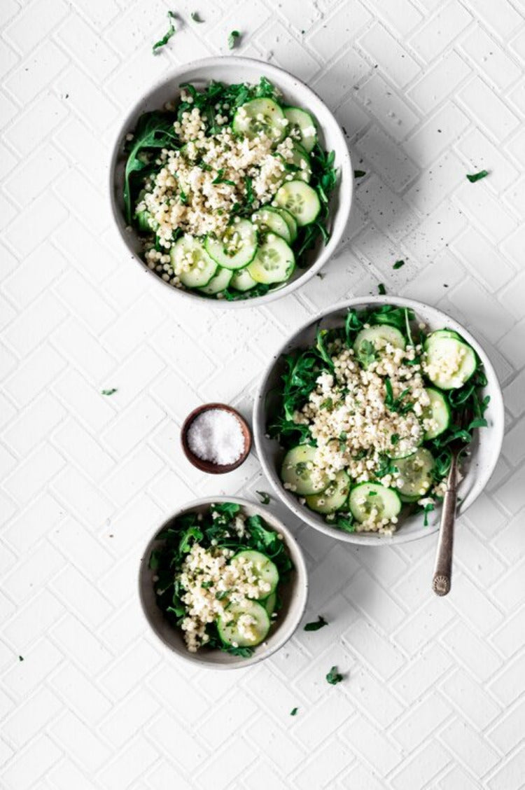 Three bowls with salad cucumber arugula millet small bowl with salt top view isolated on white background