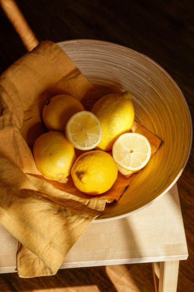 Lemons on linen cloth in wooden bowl warm light