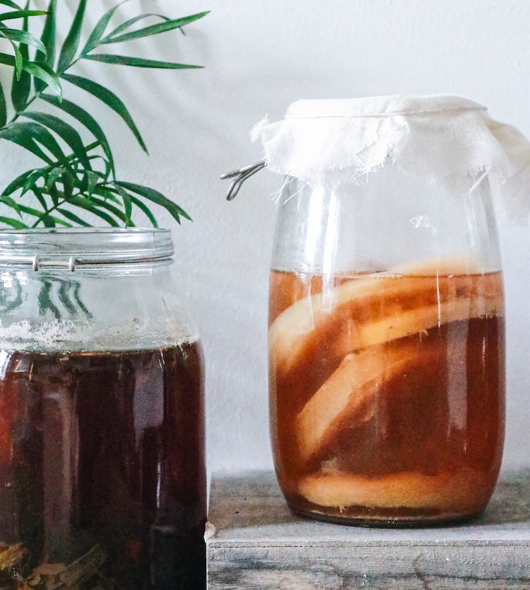 Two glass kombucha with tea mushrooms on wooden box