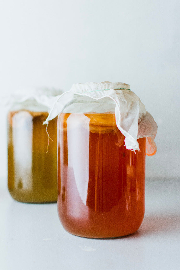 Zwei Einmachglaeser mit Kombucha mit Baumwolltuch abgedeckt