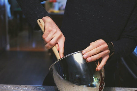 Woman touches dough in mixing bowl