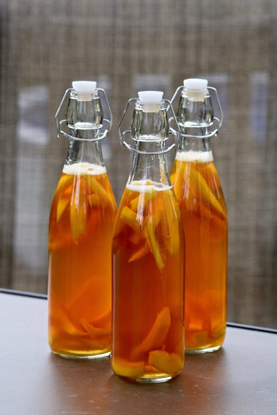 Three bottles of kombucha secondary fermentation with pieces of apple