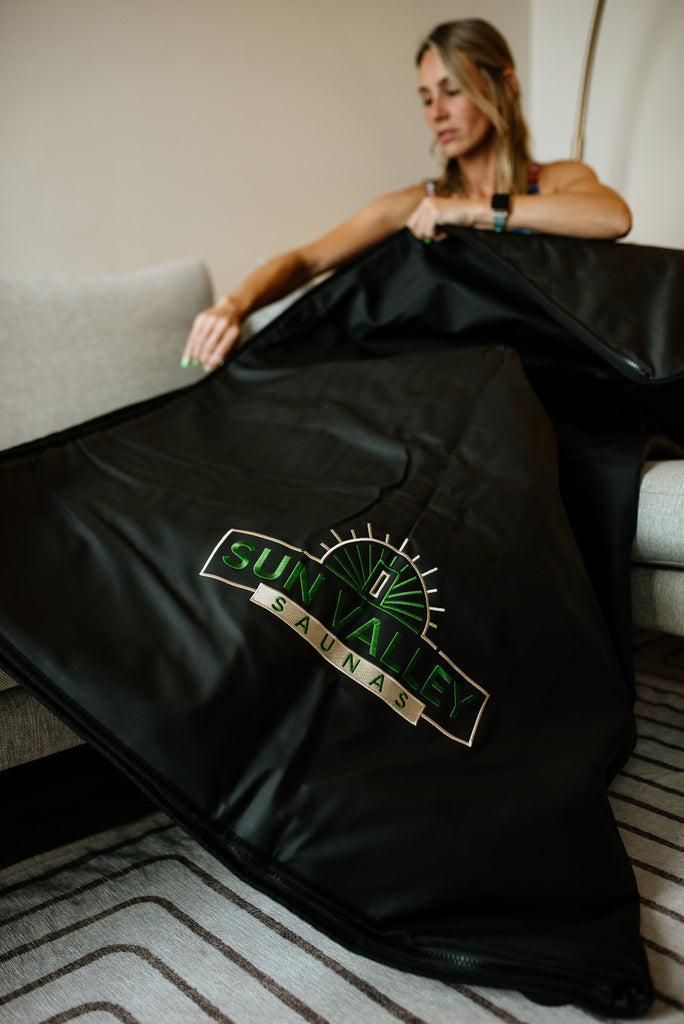 A woman sitting beside an infrared sauna blanket