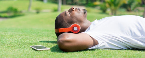 Homem deitado na grama com fone de ouvido