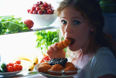 Mulher comendo na porta da geladeira