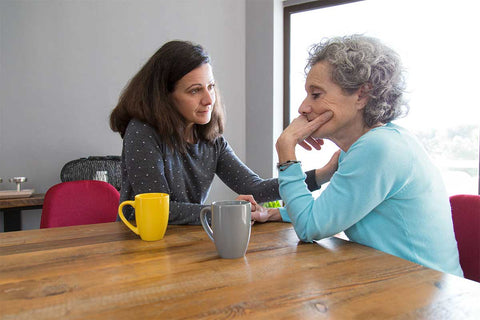 Duas mulheres conversando sentadas em uma mesa