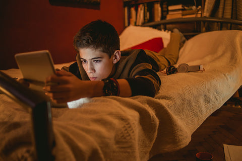 menino usando celular na cama