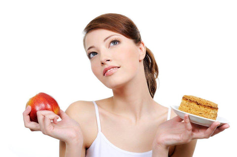 Mulher segurando um bolinho e uma maçã