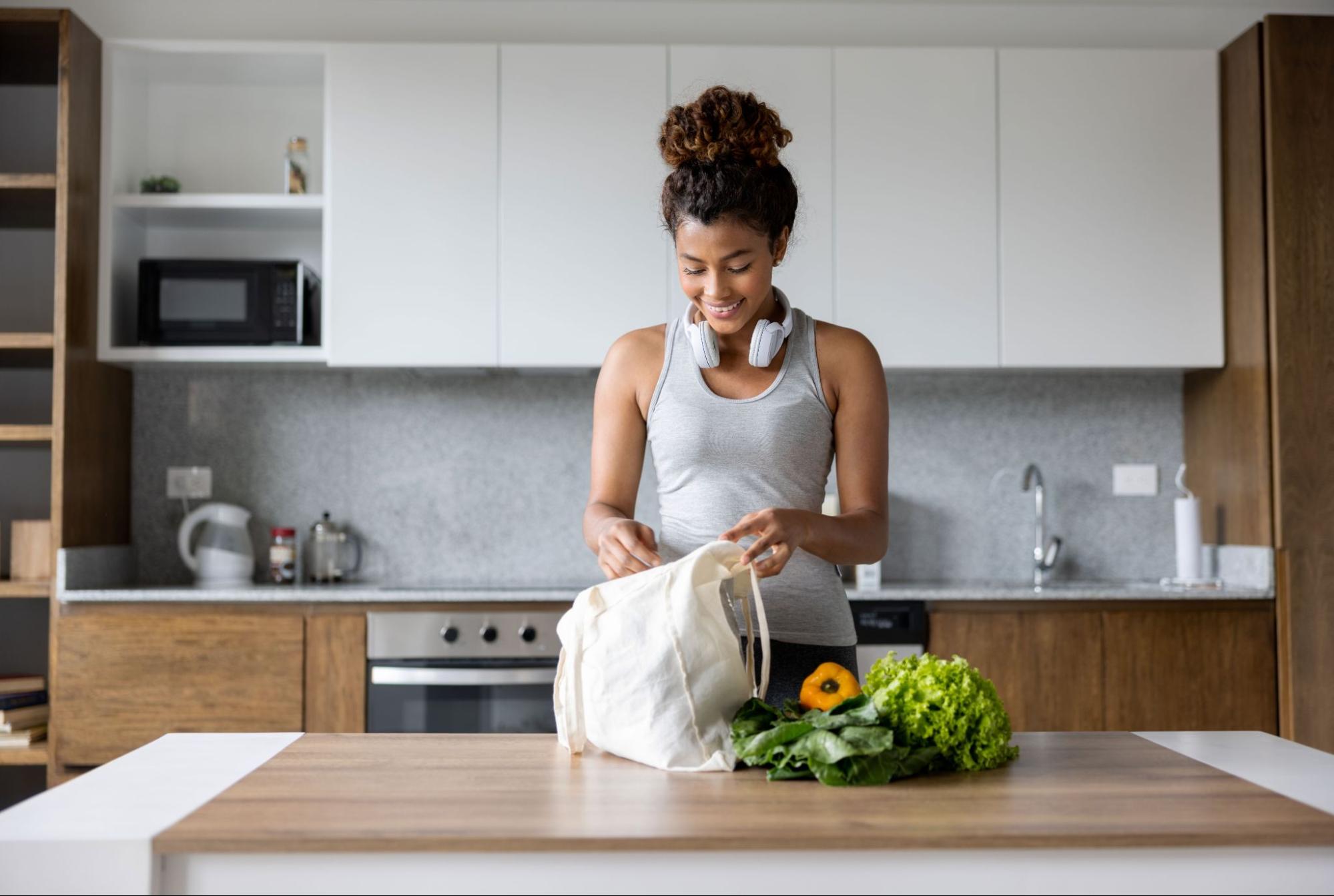 young woman unpacking groceries in workout gear