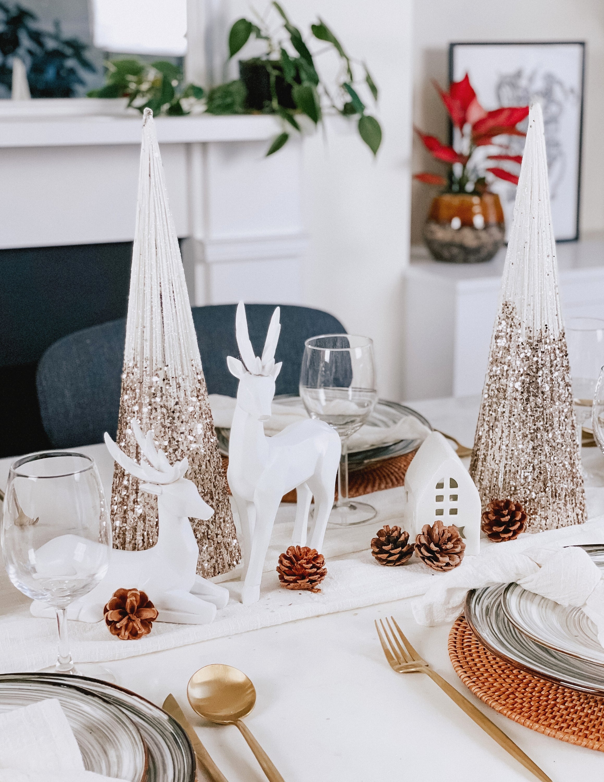 What a Host Home Decor: Christmas Tablescape With Geometric Decorative Christmas Deers, Scandi Houses, Rattan Placemats, White and Gold Christmas Table Pine Trees, Porcelain Plates Set Tableware, Gold Cutlery Stainless Steel Set and Rustic Cotton Gauze Table Textiles