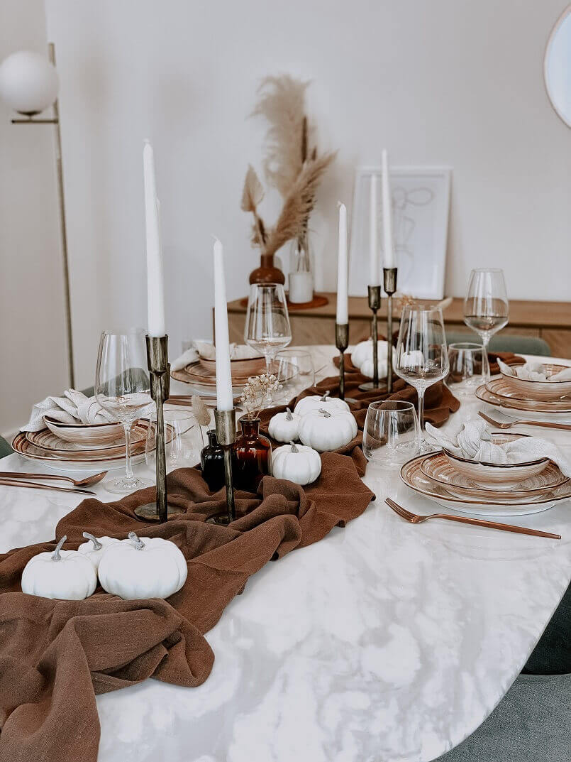 Autum Tablescape from What a Host Home Decor with cotton gauze table runner, brass gold candle holders, vanilla taper candles, porcelain plates and cooper stainless steel cutlery