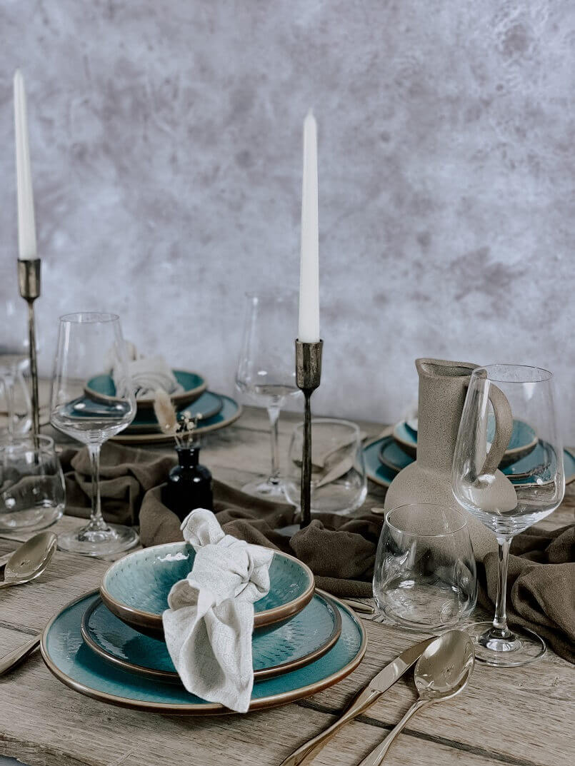 Tablescape from What a Host Home Decor with porcelain plates, brass candle holders, vanilla taper candles, gold cutlery set and cotton gauze table runner