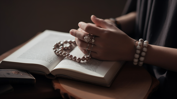Close-up of a person wearing symbolic jewellery while engaged with a scientific book, illustrating the paradox of rationality and irrational symbolism