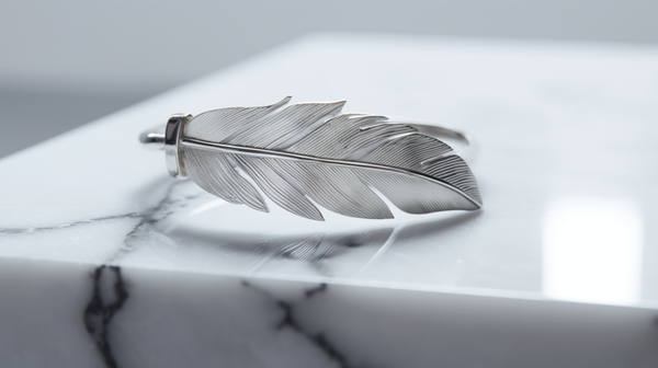 Overhead shot of a silver bracelet with a feather motif, symbolizing freedom and independence.