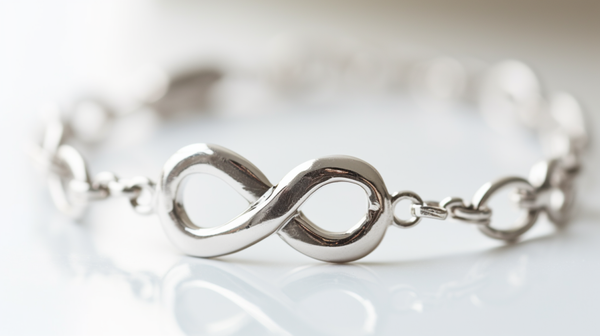  Infinity symbol bracelet on a white marble surface, symbolizing eternal love or friendship.