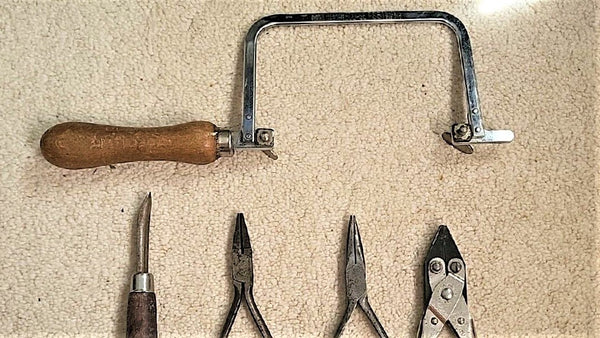 Jewellers essential hand tools  saw frame, pliers and a burnisher