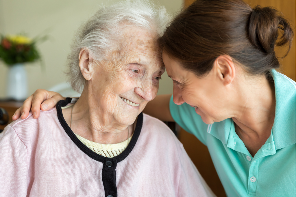 younger woman comforting older woman as she smiles