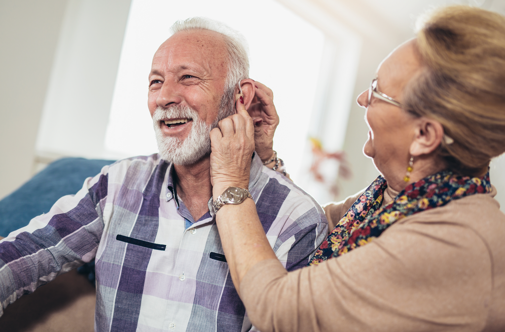 older woman checking ear of older man for hearing loss