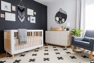 Wooden cot in nursery with a dark feature wall