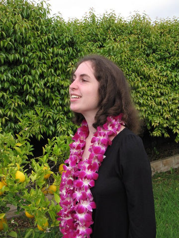 Gina Marinello-Sweeney near tree and shrubbey on college graduation day.