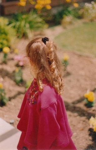 Gina Marinello-Sweeney as a little girl in hot pink gazing at garden.