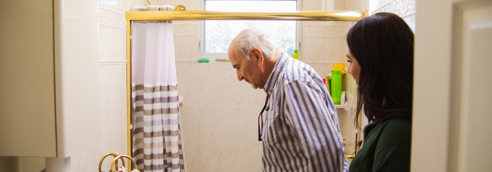 older adult standing in bathroom with occupational therapist