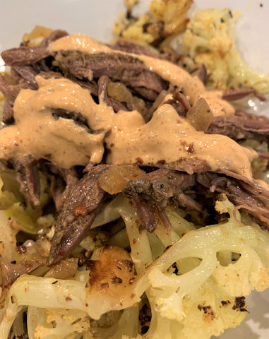 cooked beef brisket with a Mexican style barbacoa sauce, served over a bed of roasted cauliflower