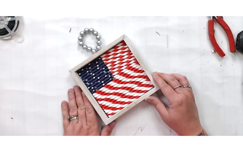 a shadowbox filled with an American flag made from paper straws