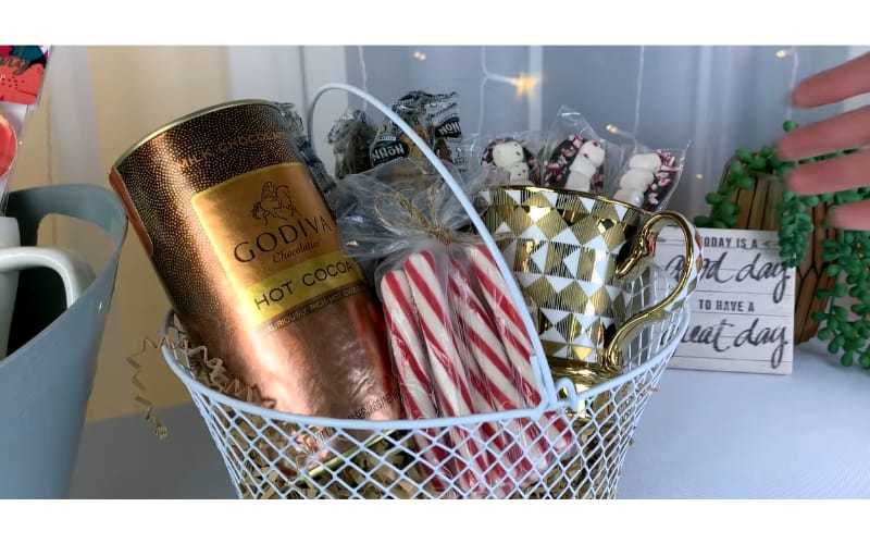 hot chocolate-themed gift basket filled with hot choco powder, mug, and treats