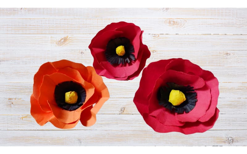 Poppy flowers made from construction paper on a distressed table