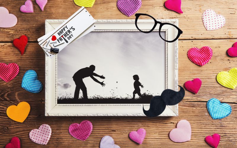 A DIY frame of a father and child with hearts strewn over the table