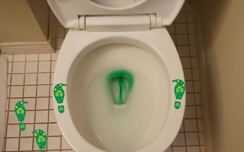 Toilet with green water flushing and leprechaun footprint stickers