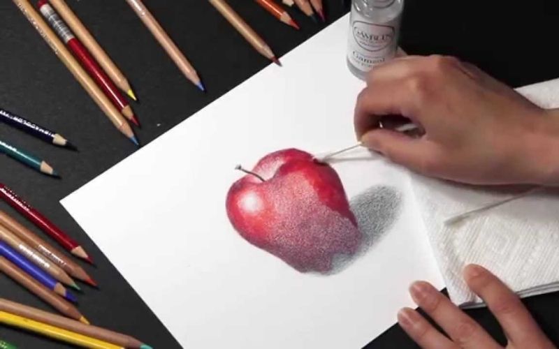 An artist blending a colored pencil drawing using a solvent