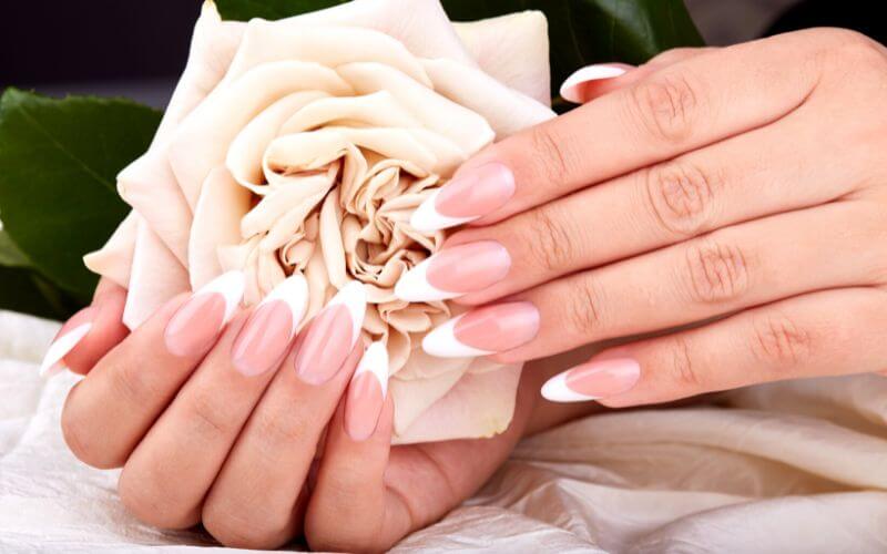 a woman's nails with polish, holding a flower