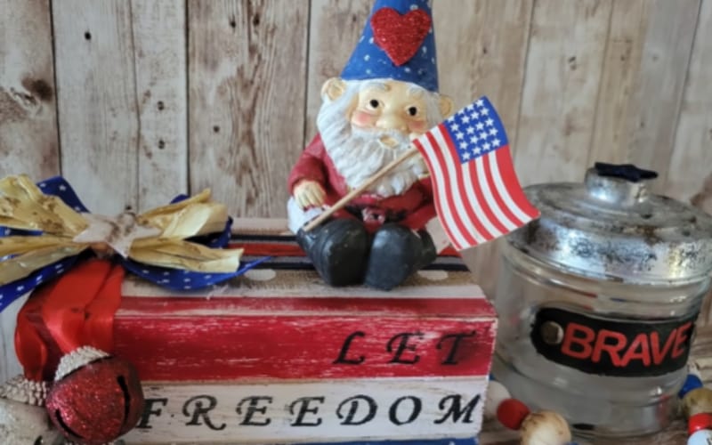 a cute gnome in patriotic colors holding an American flag 