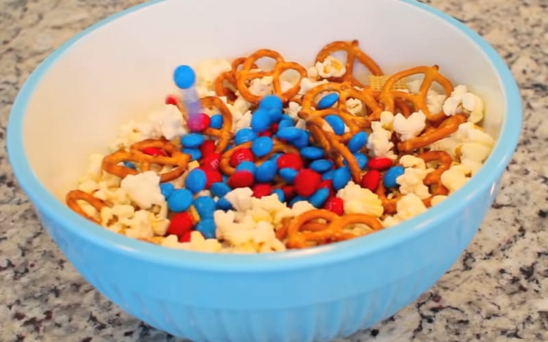 a homemade Chex mix with M&amp;Ms in a blue bowl
