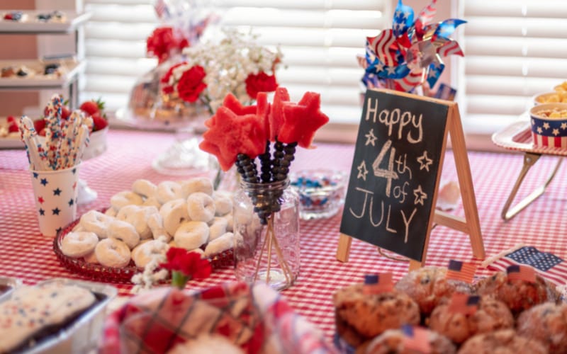  a party table decorated with 4th of July decors and laden with festive food