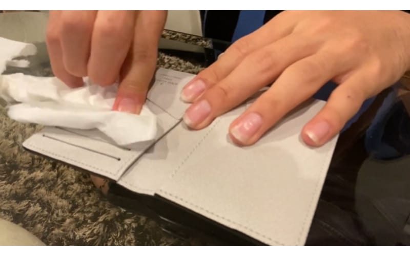 an image of a crafter removing the excess body lotion on the leather wallet