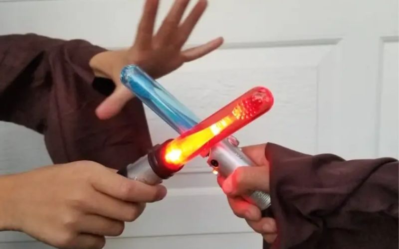kids holding two lightsaber toothbrushes