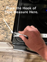 How to measure a stove top cover. Image showing a tape measure placed on the left side of the stove top to measure for a noodle board.