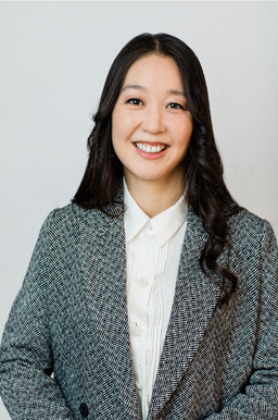 A woman in corporate attire smiling and posing for a professional headshot.