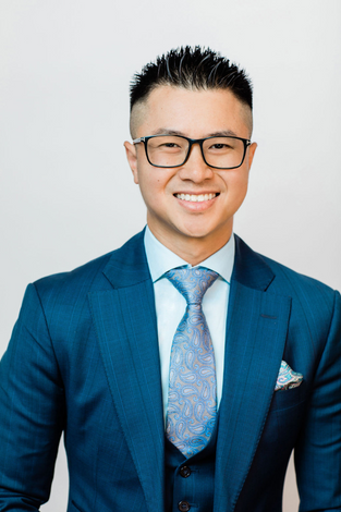 A young man in a suit smiling for his professional headshots.