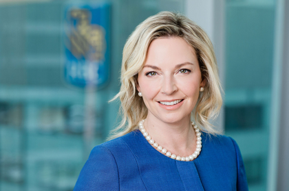 A smiling woman wearing blue corporate attire, prepared for a professional headshot.