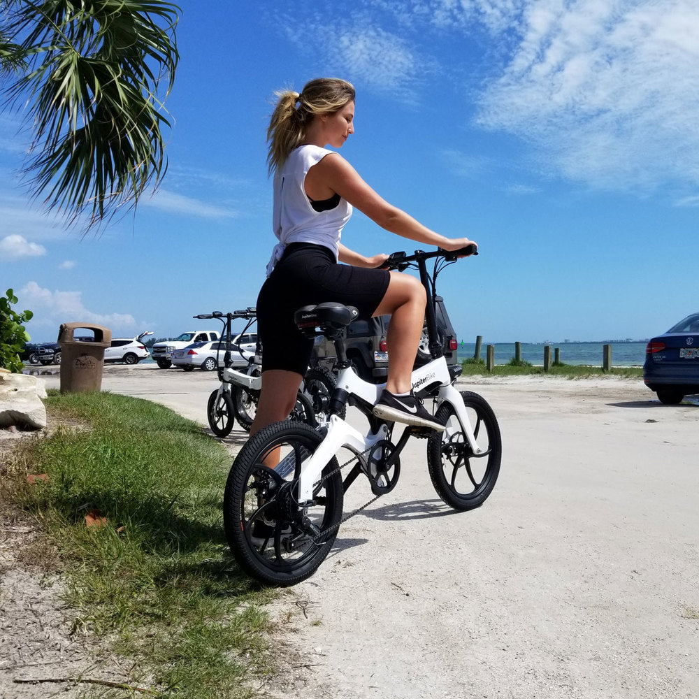 Woman riding Jupiter Bike Discovery x7 Folding Electric Bike by the beach