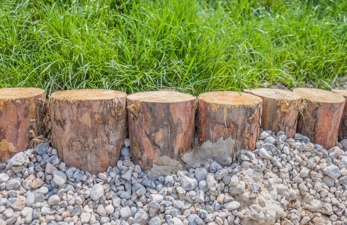 Rasenkante aus Holzstämmen und Kies