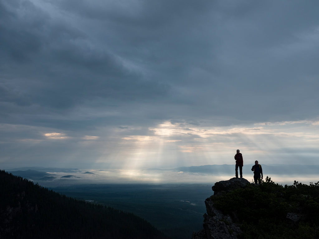 Two hikers on a mountain summit on a cloudy day