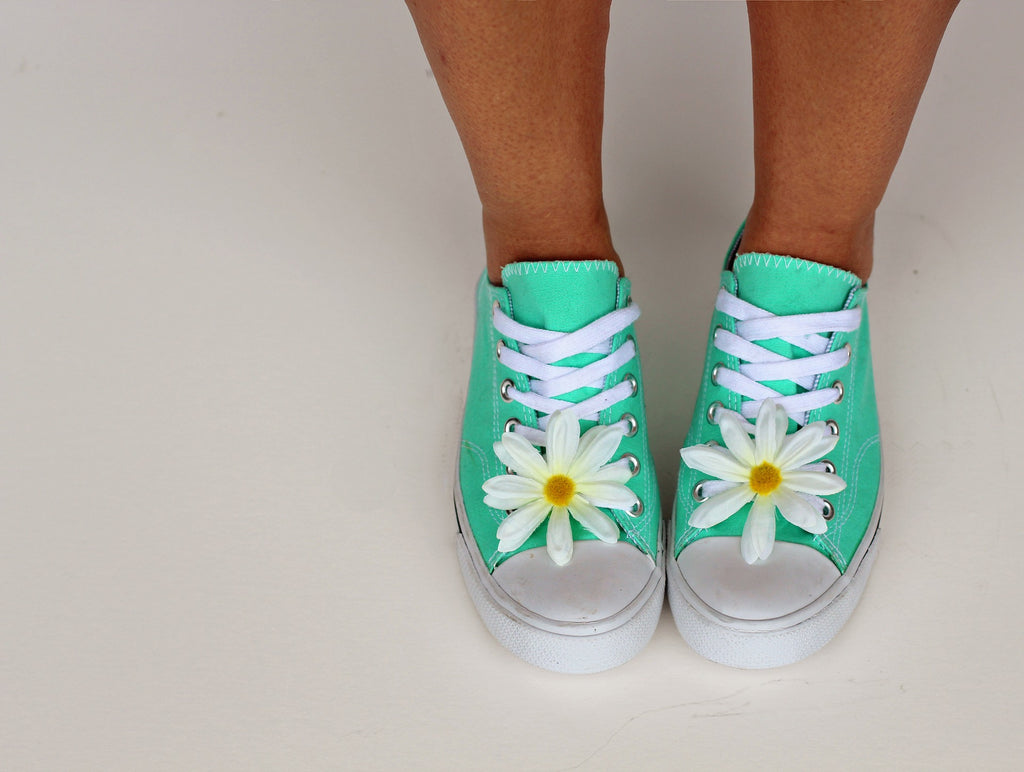 Woman wearing pair of mint coloured converse style trainers.