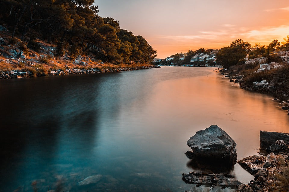 A river during autumn with rocks and distant buildings